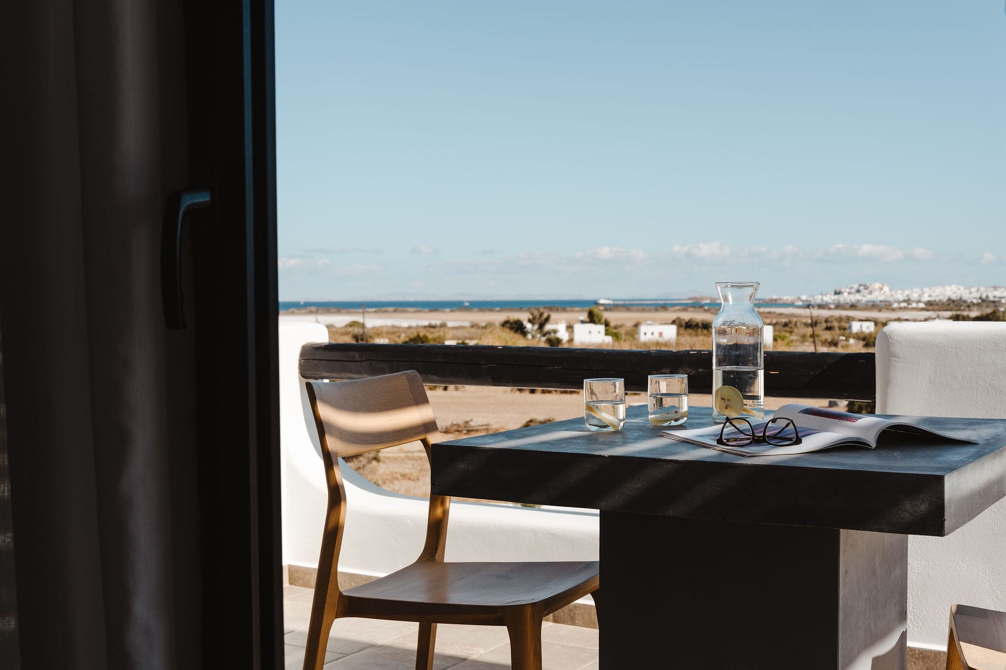 a table with glasses and bottles on it by a window overlooking a city