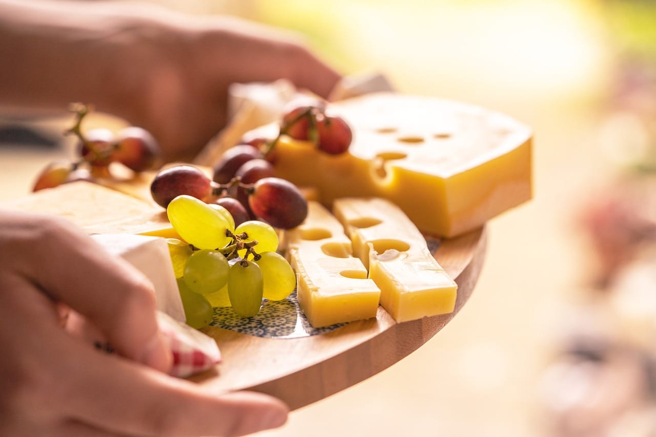 a hand holding a piece of cheese with grapes and cheese on it