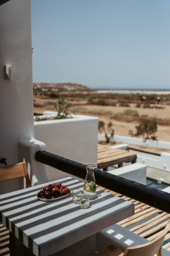 a table with a plate of food on it and a view of the beach and water