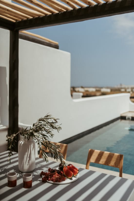 a table with a plate of fruit and a vase of fruit on it
