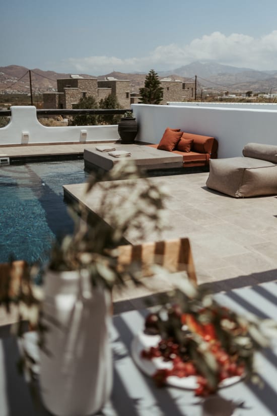 a deck with a pool and a couch and a table with food on it