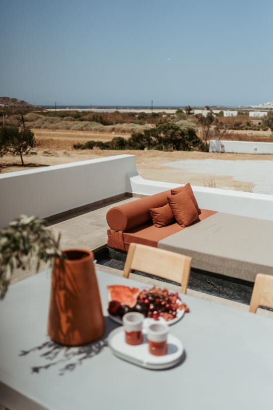 a table with food and drinks on it with a view of the ocean