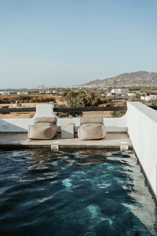 a pool with white chairs and a city in the background