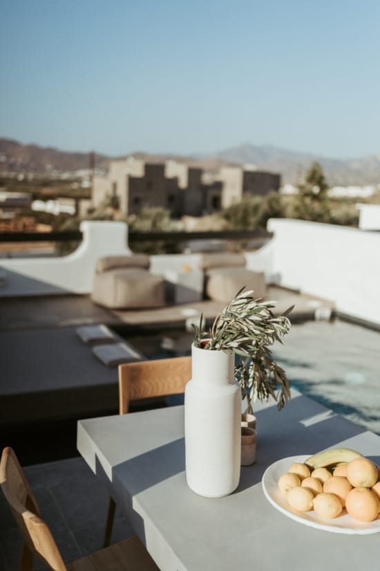 a table with a vase of flowers and a bowl of fruit on it