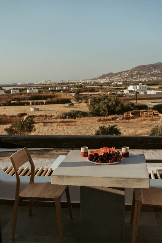 a table with a plate of food on it with a view of a town and mountains in the