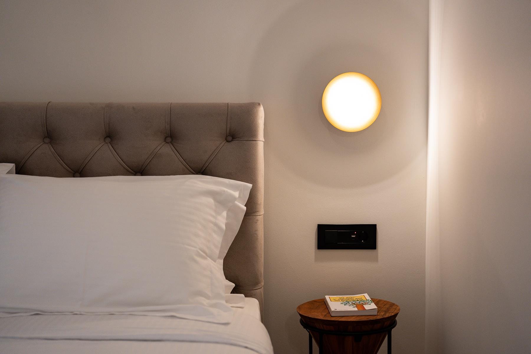 a bed with a lamp on the wall