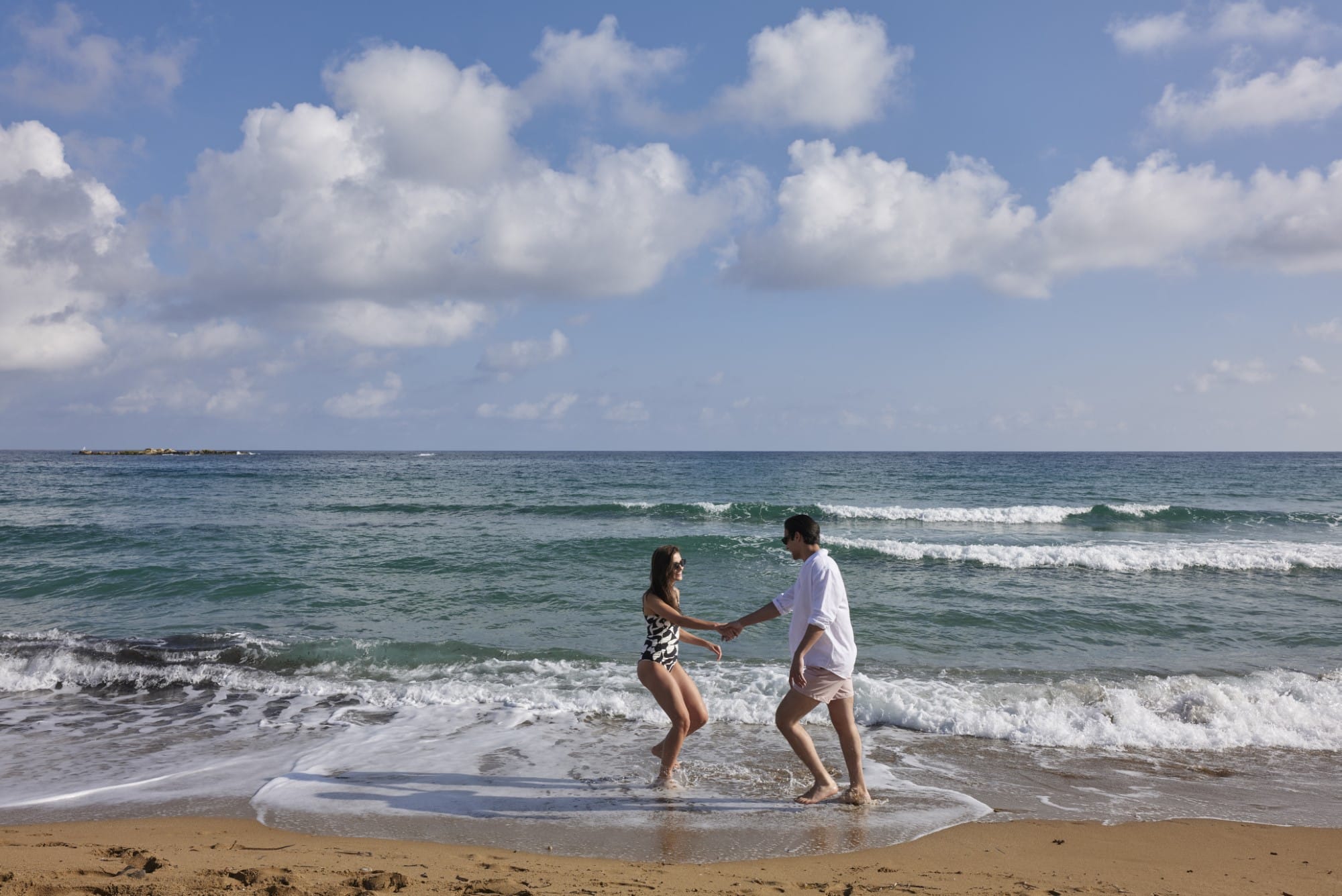 a man and a woman running into the ocean