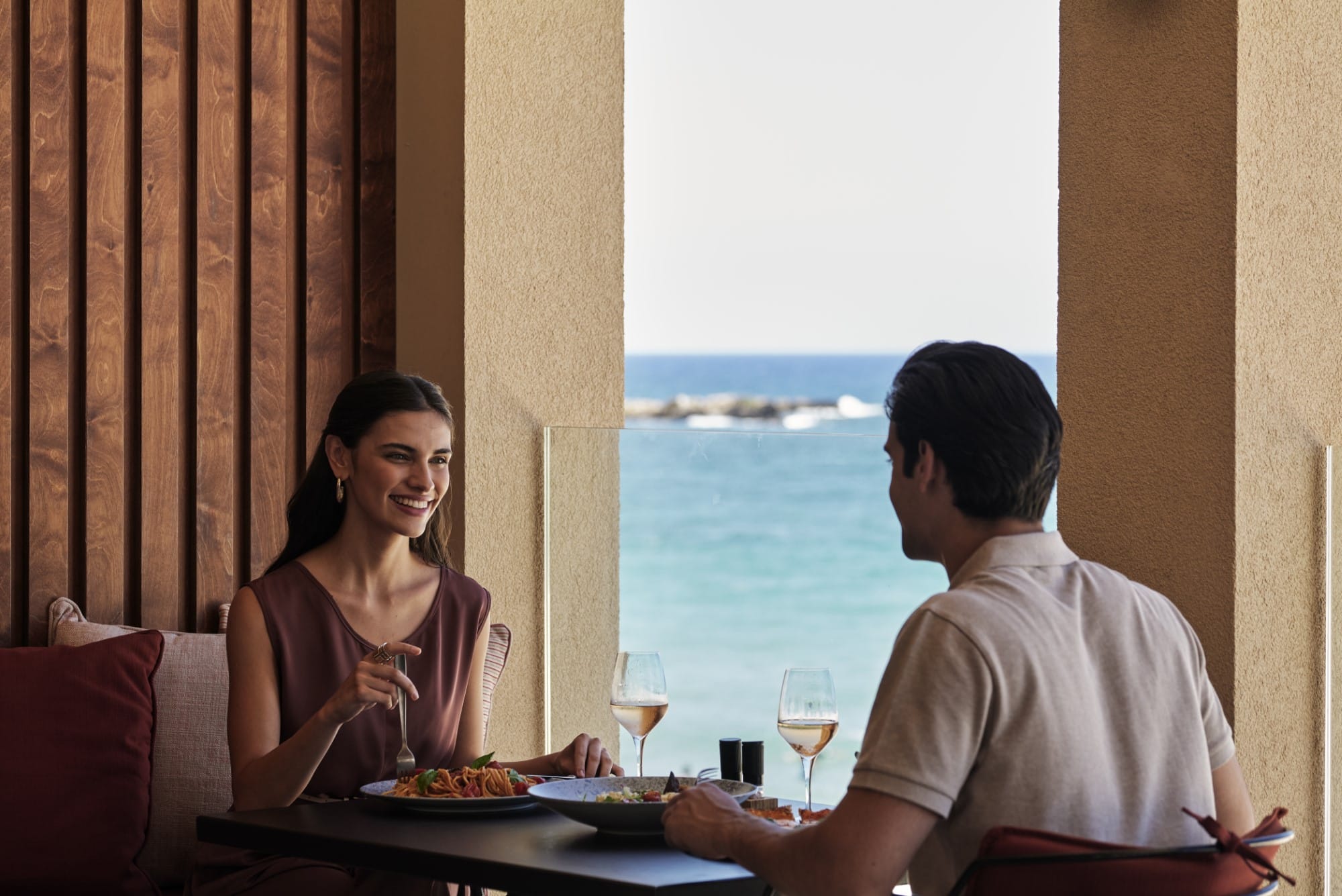 a man and a woman sitting at a table with food and drinks