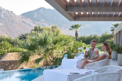 a man and woman sitting at a table by a pool