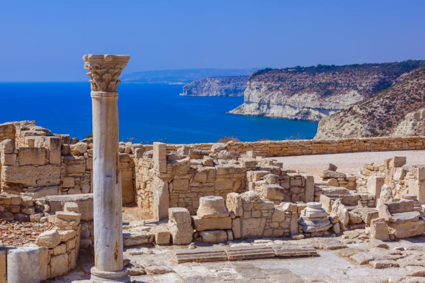 a stone wall with a body of water in the background with Delos in the background