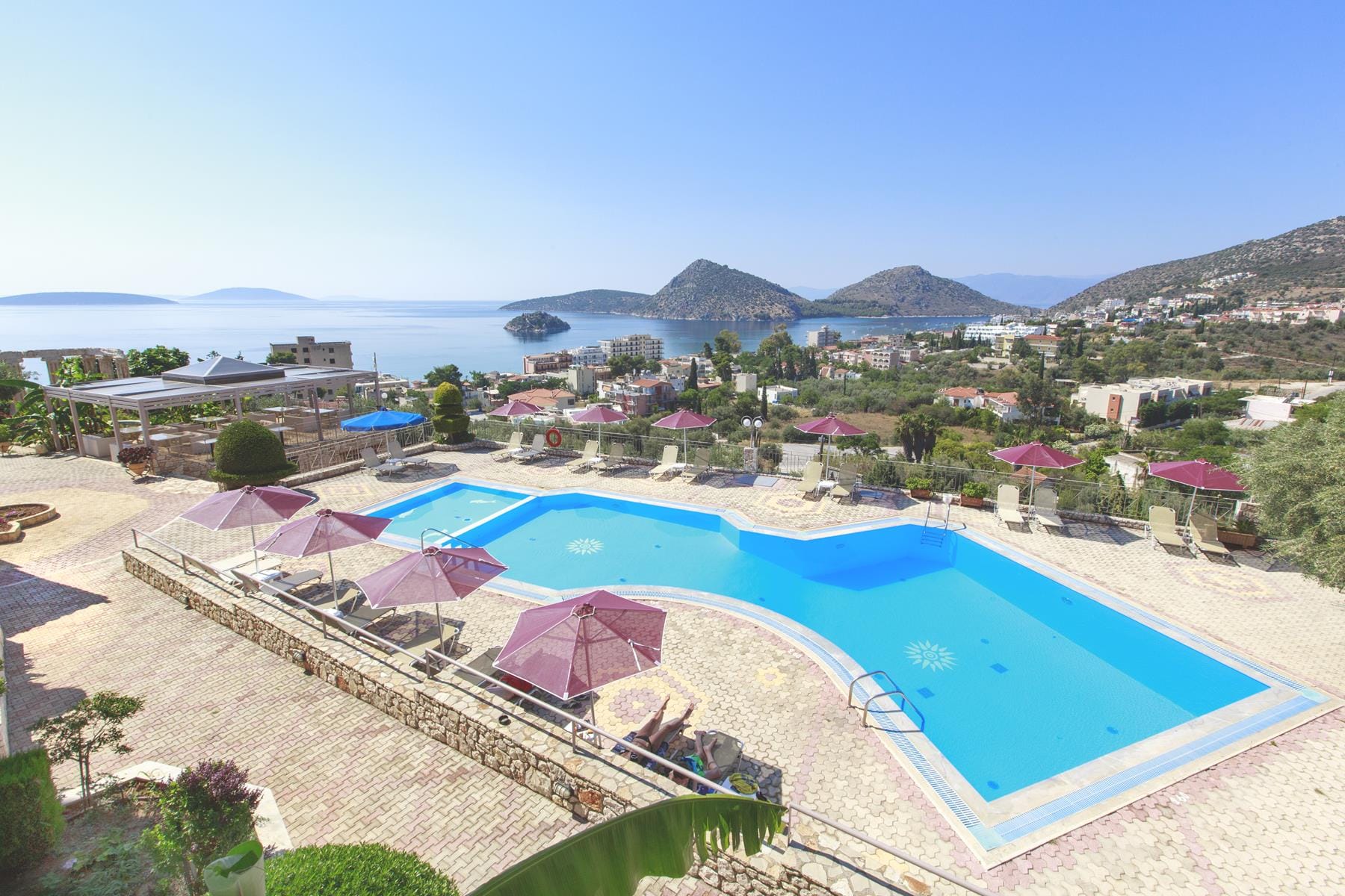 a pool with umbrellas and chairs by a beach