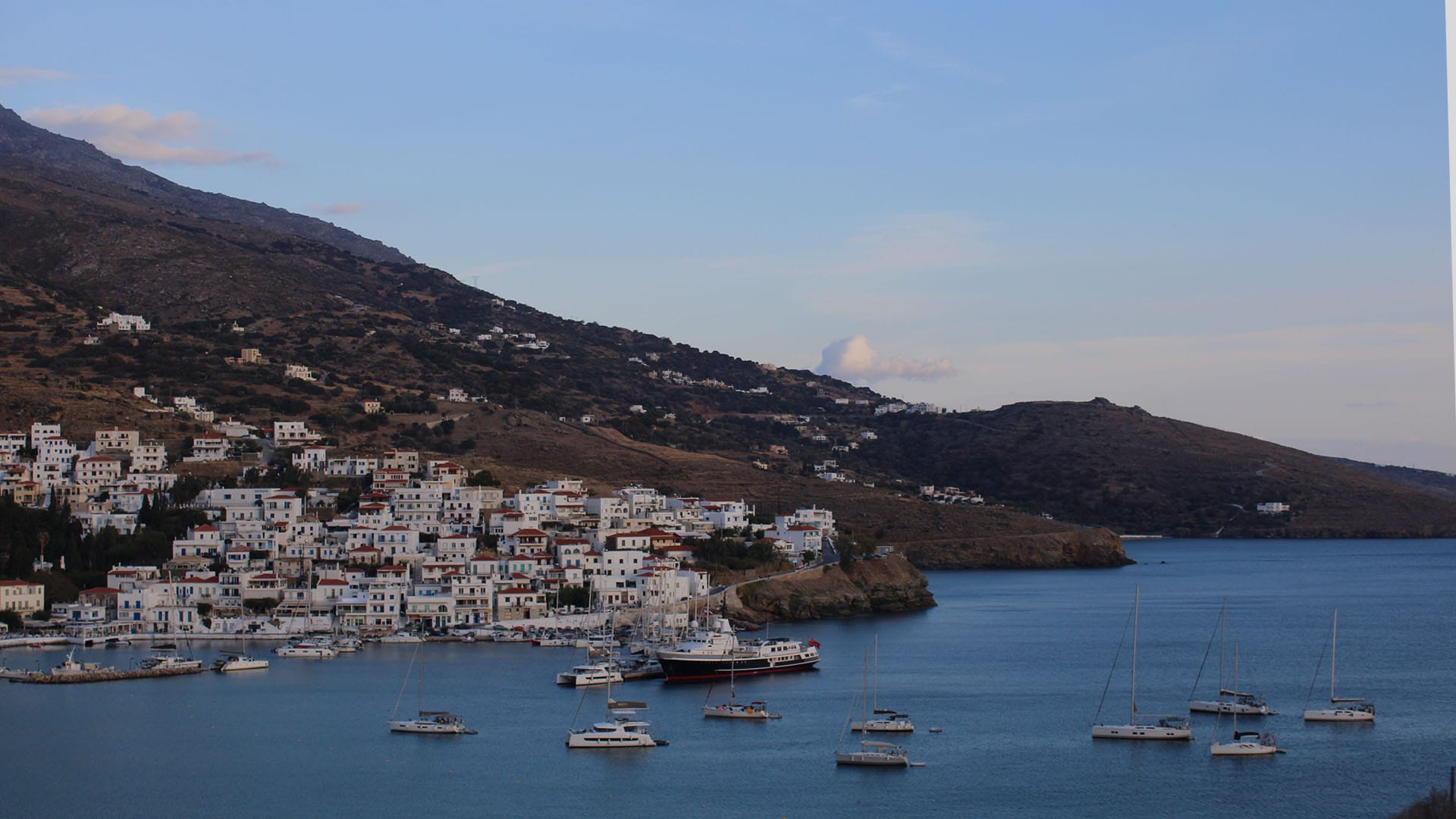 a body of water with boats and a hill in the background