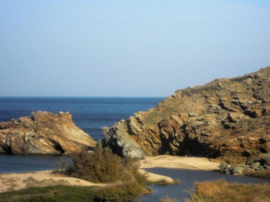 a rocky beach with a body of water in the background