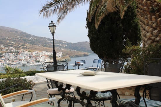 a table with chairs and a lamp on a balcony overlooking a city