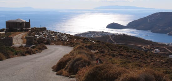 a road leading to a building on a cliff above a body of water