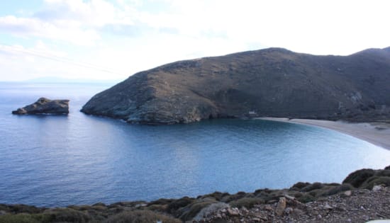 a rocky beach with a large rock in the background