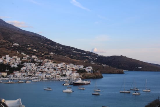 a body of water with boats in it and hills in the back
