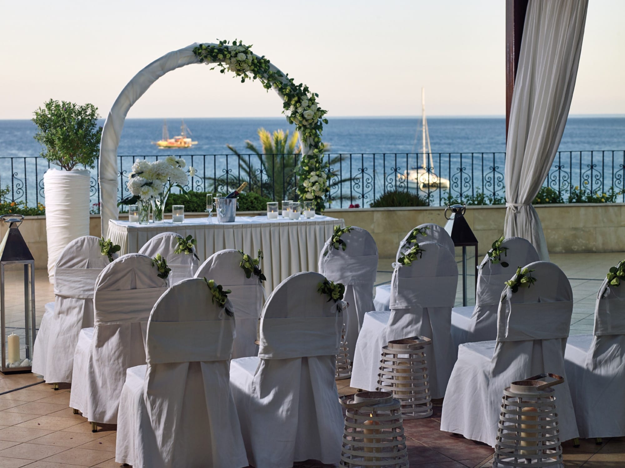 a group of white chairs with white cloths and a body of water in the background