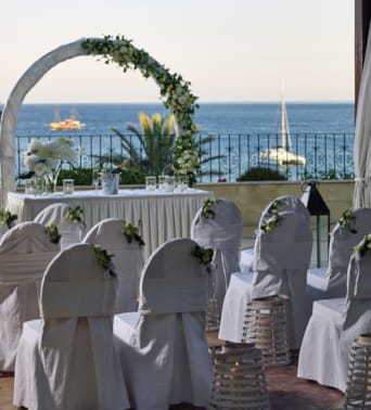 a group of white chairs with white cloths and a body of water in the background