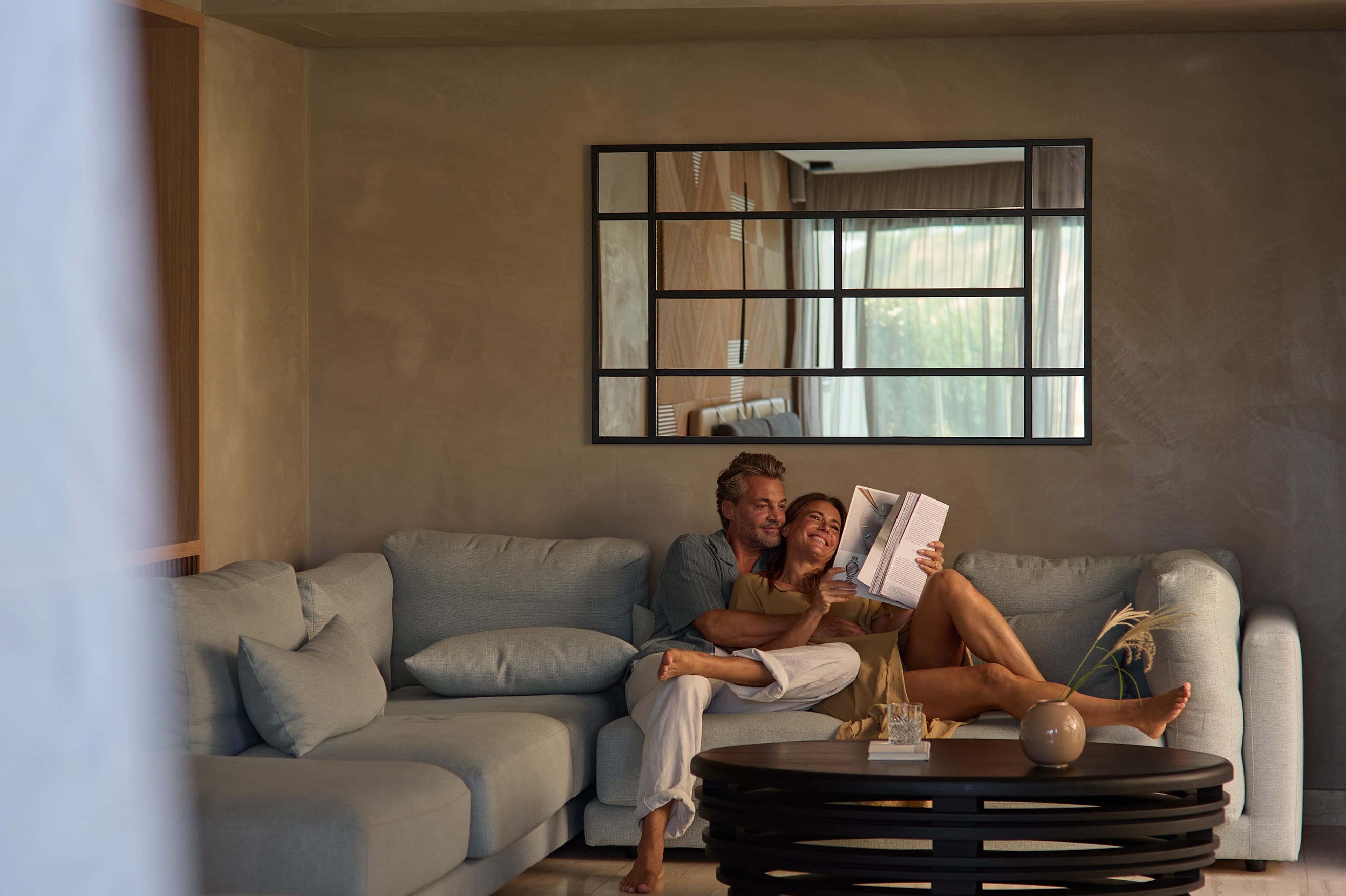 a man and woman sitting on a couch with a book