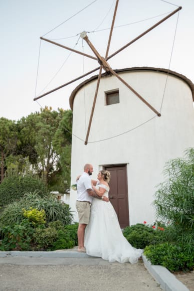 a bride and groom kissing in front of a windmill