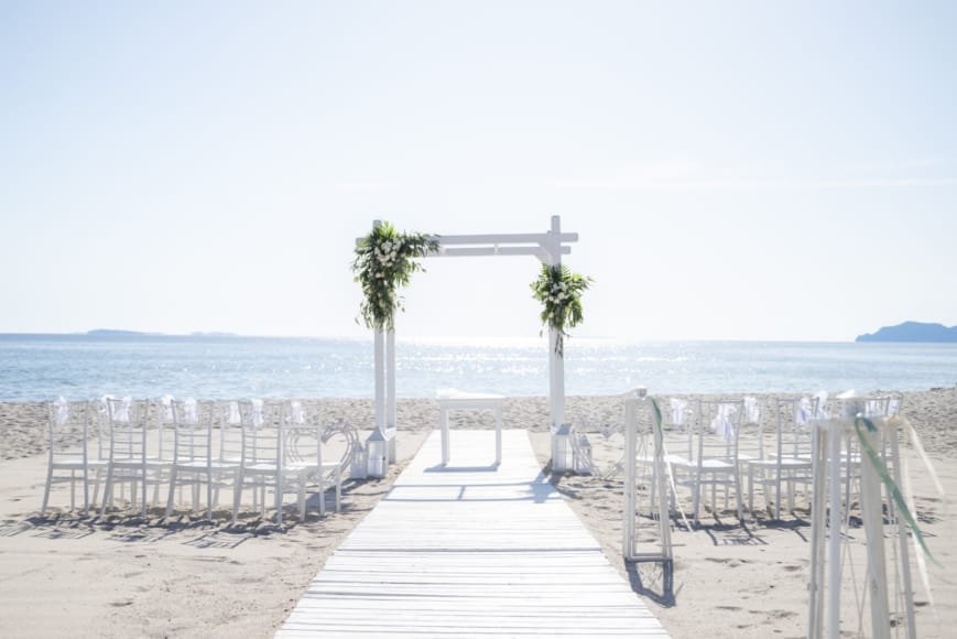 a boardwalk with palm trees and a body of water in the background