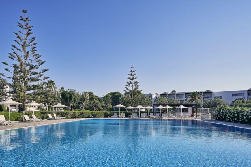 a pool with trees and buildings in the background