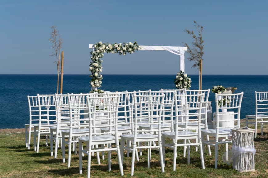 a row of white chairs on a beach