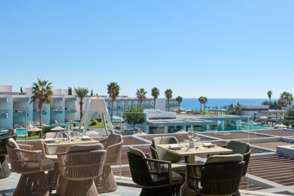 a patio with tables and chairs by a pool