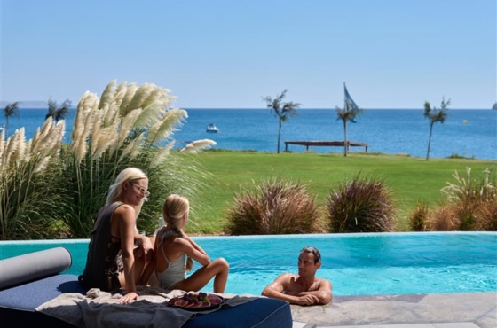 a group of people sitting by a pool with a body of water in the background