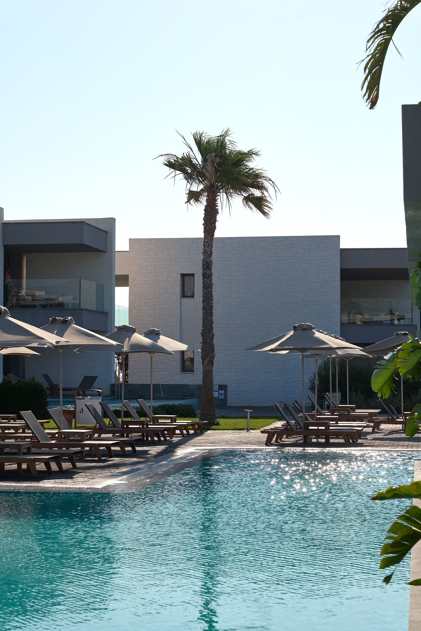 a pool with lounge chairs and umbrellas by a building