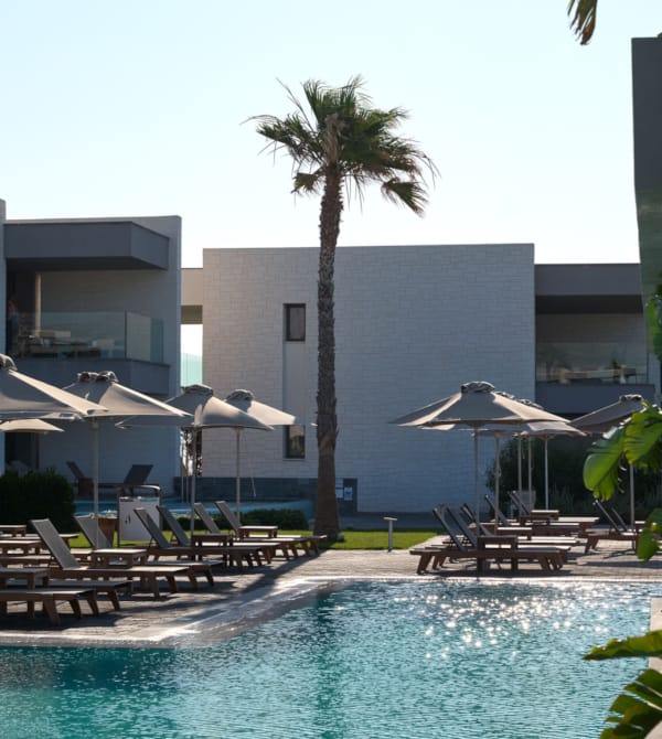 a pool with lounge chairs and umbrellas by a building