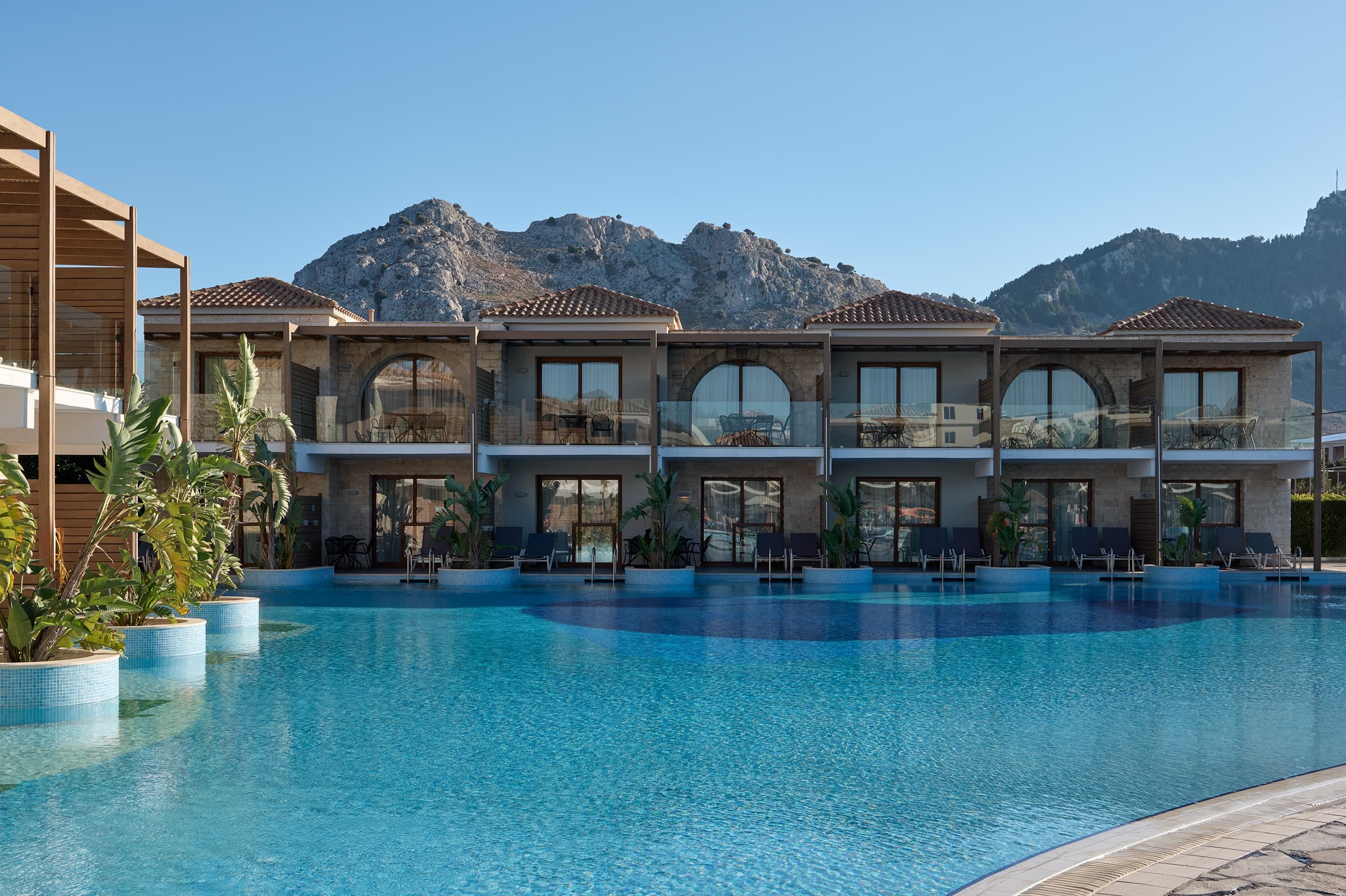 a swimming pool in front of a building with a mountain in the background