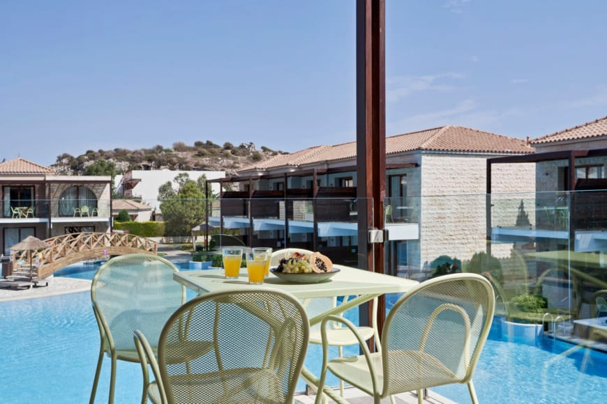 a table with chairs around it by a pool with a building in the background