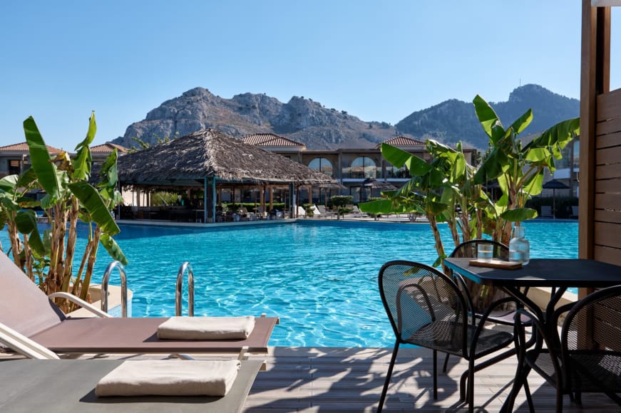 a pool with a house and mountains in the background