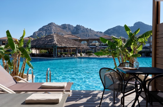 a pool with a house and mountains in the background