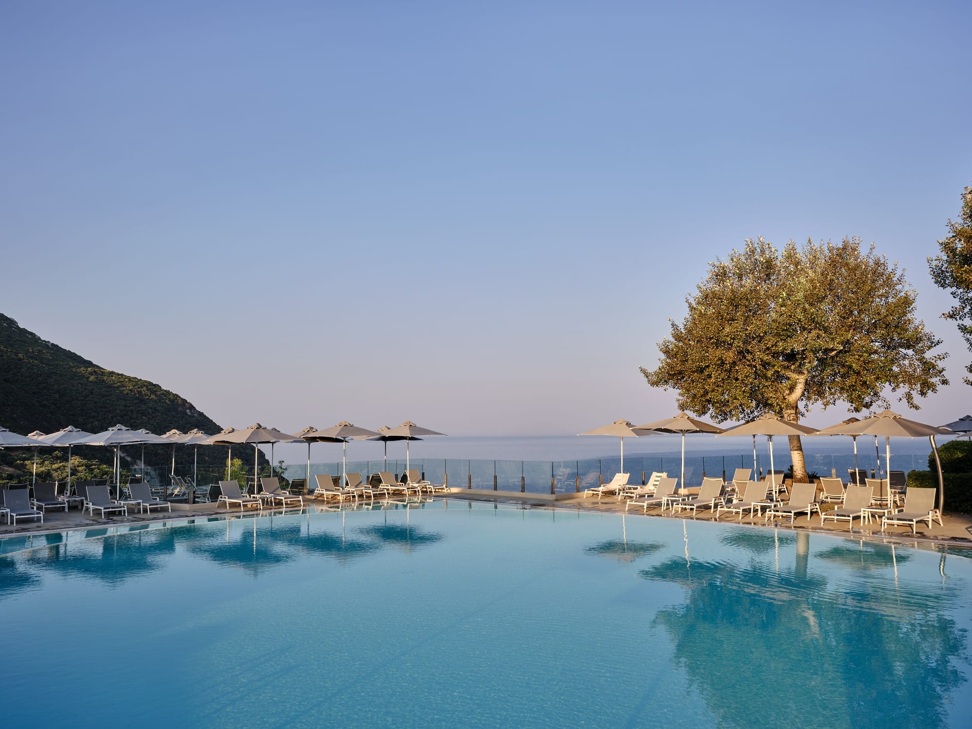 a pool with umbrellas and chairs by a beach