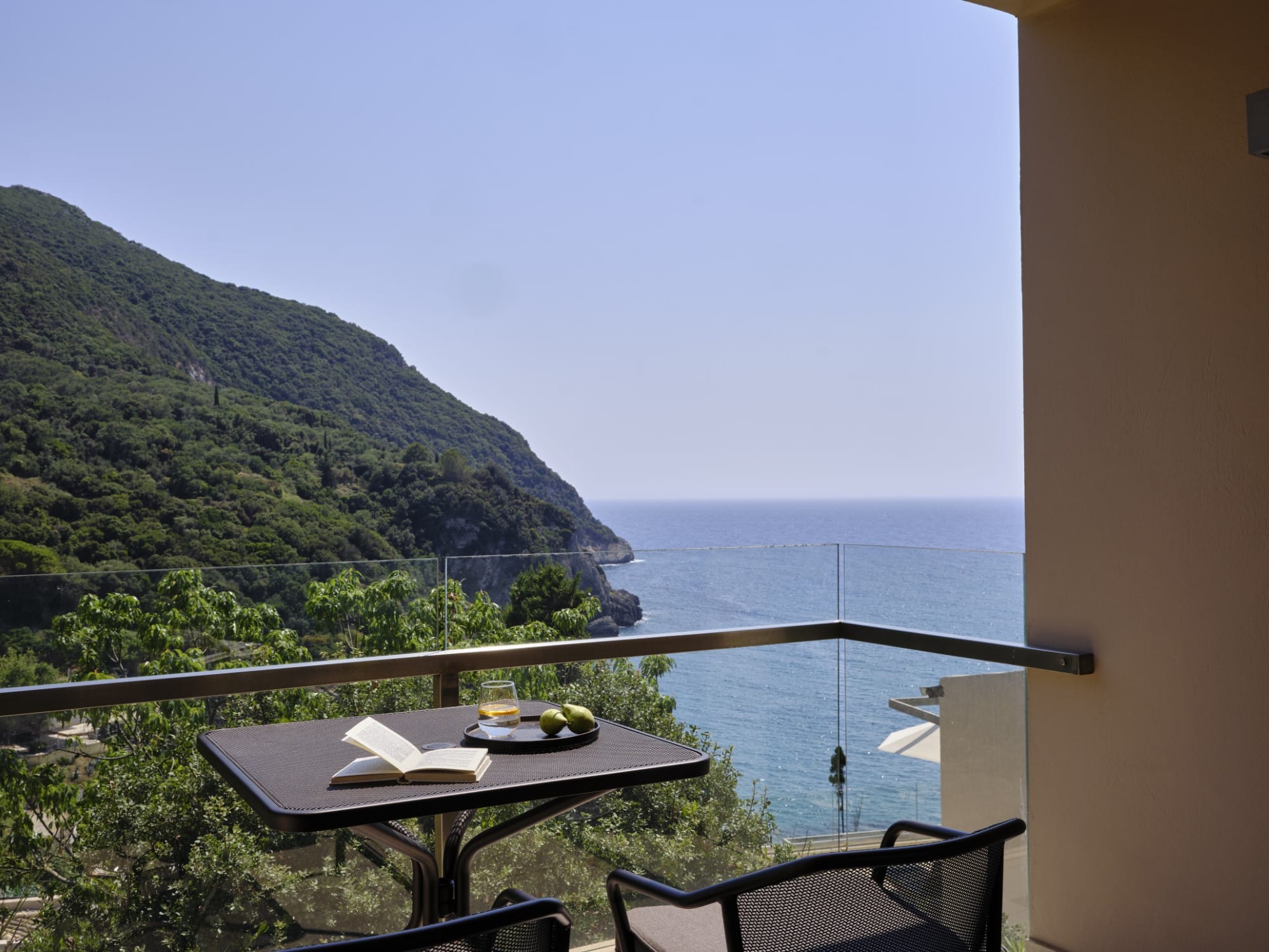 a table with a plate of food on it by a railing and a body of water