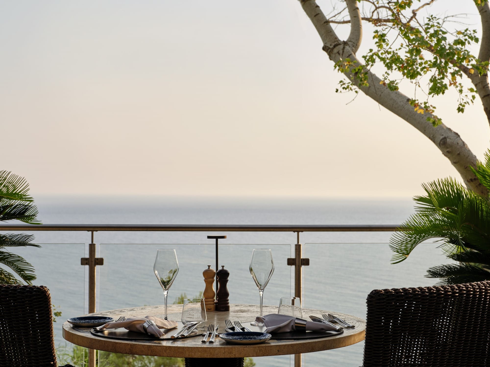 a table with wine glasses and bottles on it by a body of water