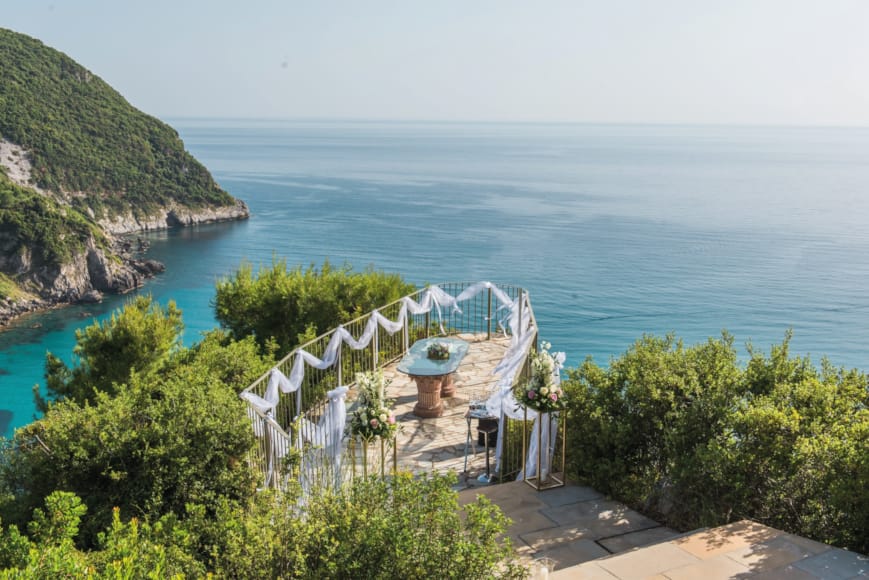 a white building on a cliff above a body of water