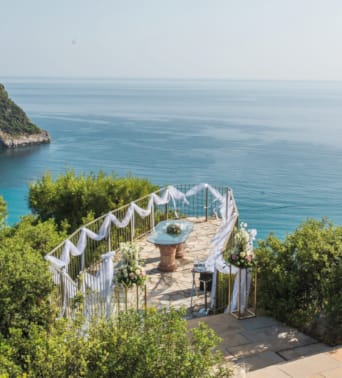 a white building on a cliff above a body of water