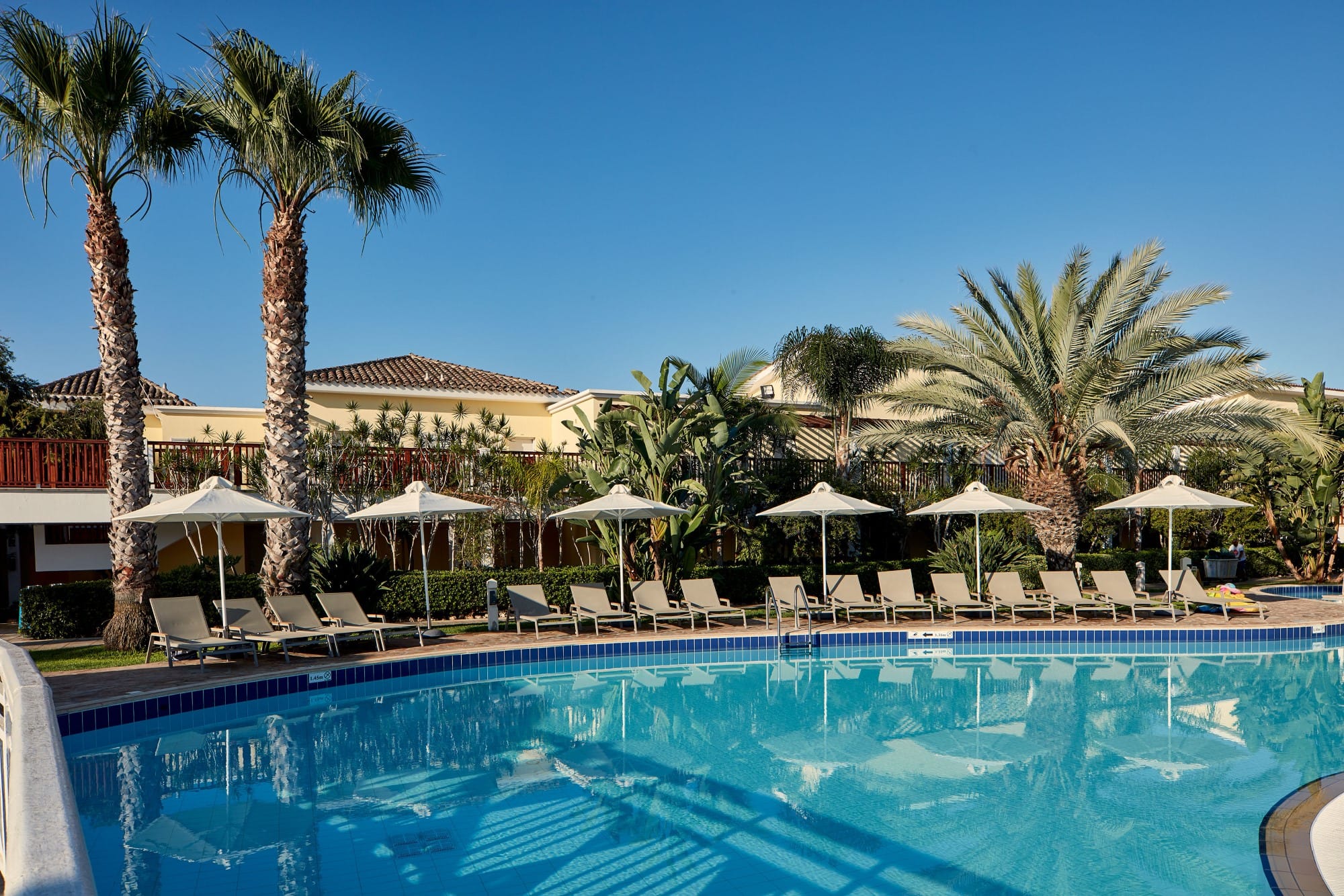 a pool with umbrellas and chairs by a beach