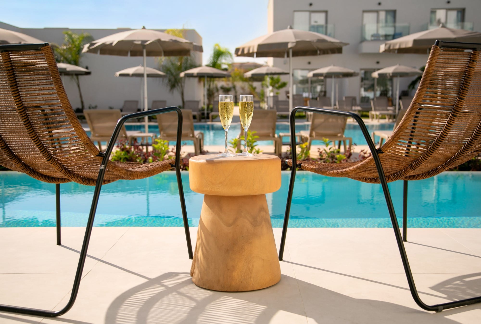 a table with glasses and umbrellas by a pool