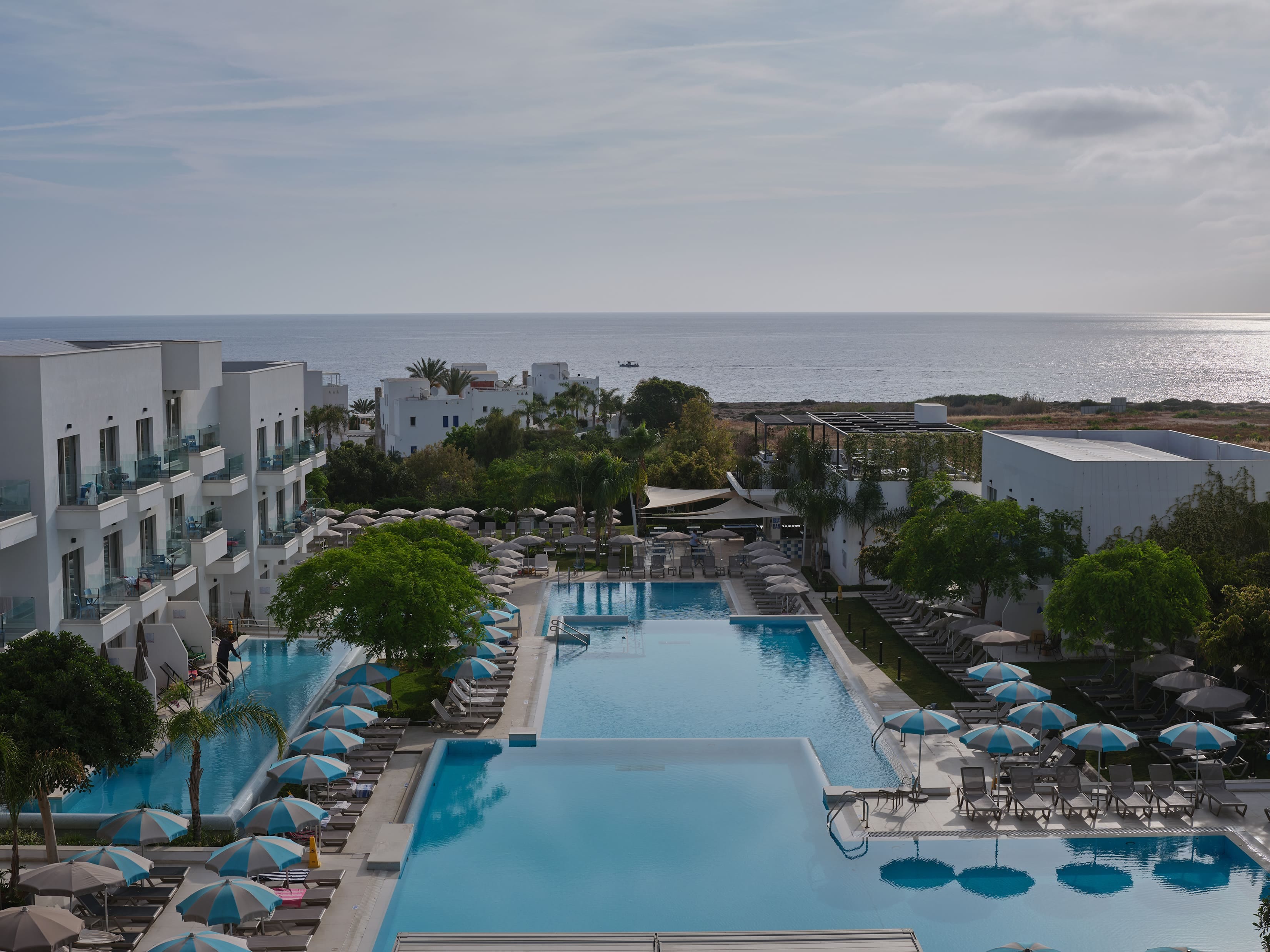 a pool with umbrellas by a beach