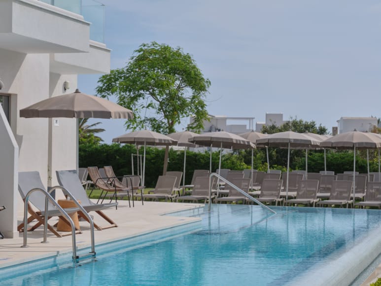 a pool with chairs and umbrellas by it