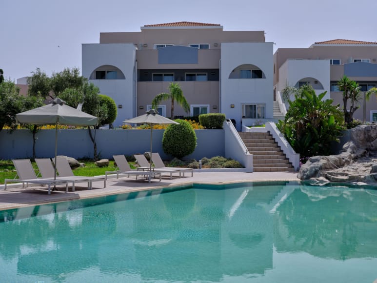 a pool with chairs and umbrellas by a building