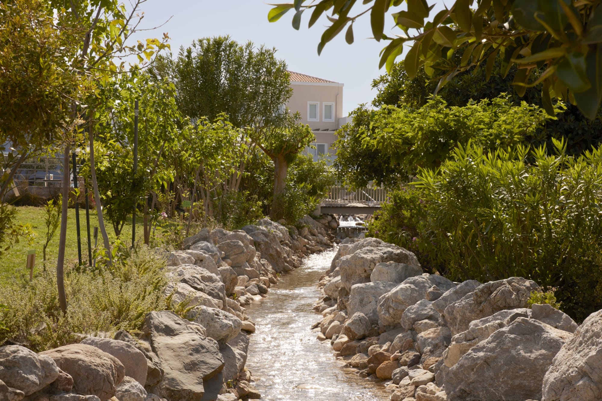 a rocky river with trees and a building in the background