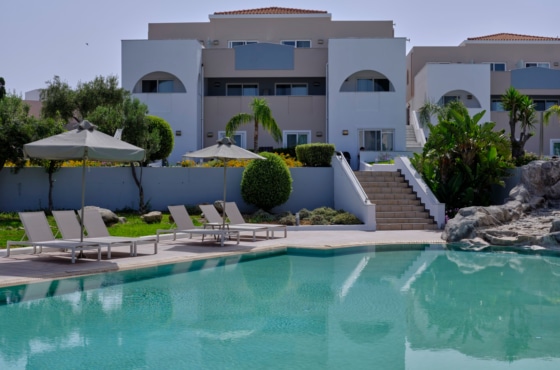 a pool with chairs and umbrellas by a building