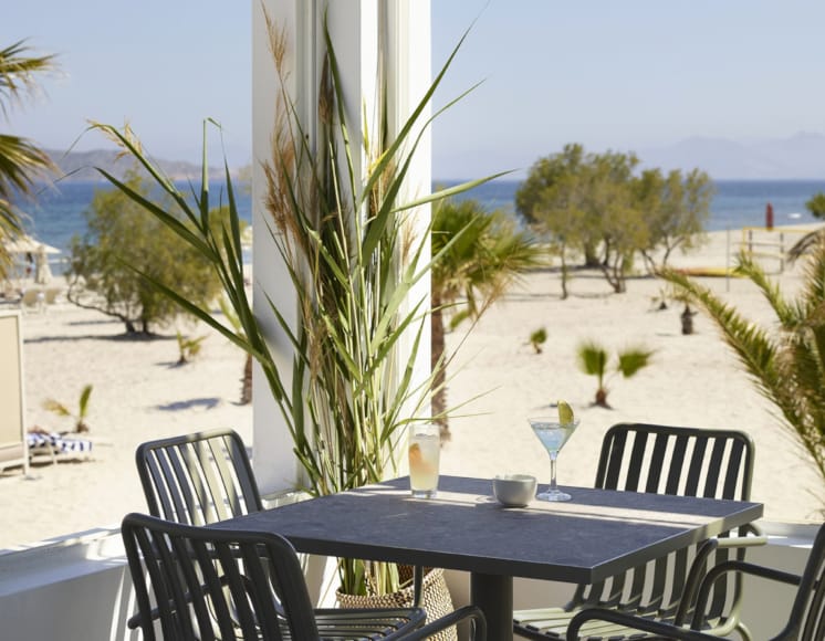 a table with glasses and a drink on it by a beach