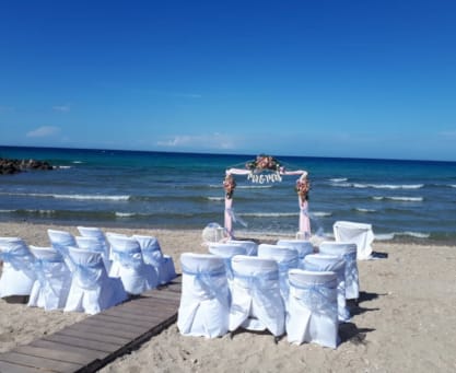 a group of people standing on a beach with chairs and tables